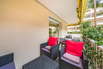 a balcony with wicker chairs and red pillows at 3 pièces au calme avec terrasses et verdure in Cannes