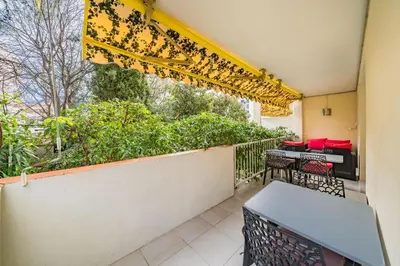 a balcony with a table and chairs and a window at 3 pièces au calme avec terrasses et verdure in Cannes