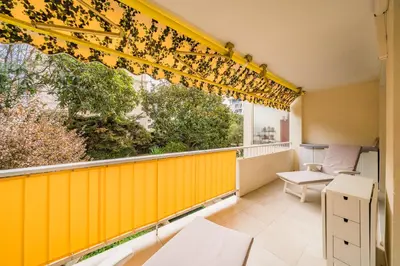 a balcony with a yellow wall and a window at 3 pièces au calme avec terrasses et verdure in Cannes