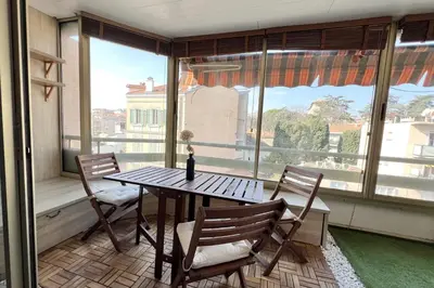 a table and chairs in a room with a large window at T2 apartment with terrace in Cannes in Cannes