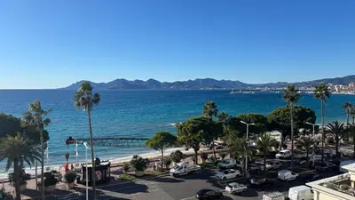a view of a beach with palm trees and the ocean at Appartement 2 pièces - Vue mer in Cannes