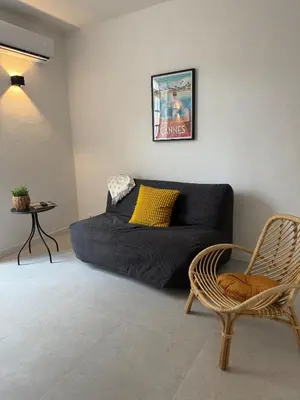 a living room with a black couch and a chair at Superbe 2P, clim, terrasse au calme, tout à pied in Cannes
