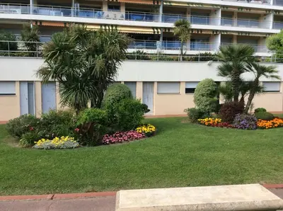 a building with palm trees and flowers in a yard at Studio cosy Cannes à 250 m de la plage, pointe Croisette in Cannes