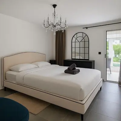 a bedroom with a large white bed and a chandelier at Palm beach apartment with swimming pool in a residence in Cannes