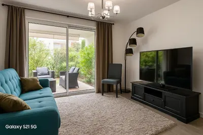 a living room with a blue couch and a television at Palm beach apartment with swimming pool in a residence in Cannes