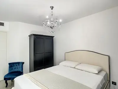 a bedroom with a bed and a chandelier at Palm beach apartment with swimming pool in a residence in Cannes