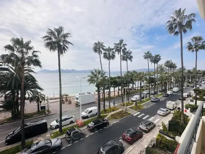 a street with parked cars and palm trees and the ocean at One bedroom apartment with a sea view right by the Croisette beaches and the center of Cannes. - 2287 in Cannes