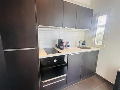 a kitchen with black cabinets and a sink at One bedroom apartment with a sea view right by the Croisette beaches and the center of Cannes. - 2287 in Cannes