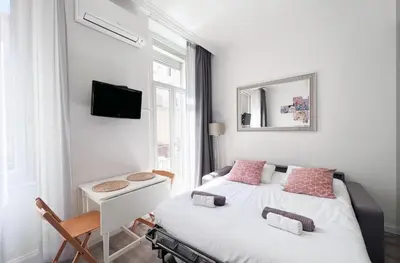 a bedroom with two beds and a desk and a mirror at Studio moderne et calme en plein centre in Cannes