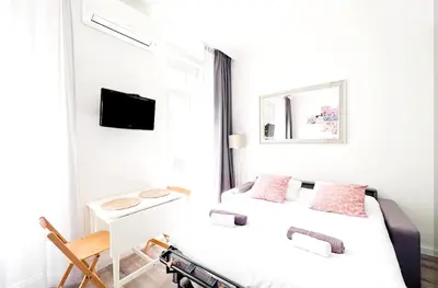 two beds in a room with a desk and a tv at Studio moderne et calme en plein centre in Cannes