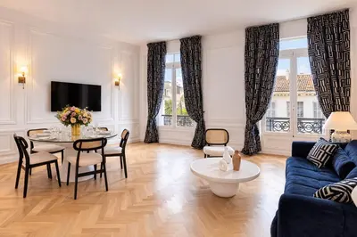 a living room with a blue couch and a table at Le Suite Napoléon - Luxe et Sérénité au Cœur de Cannes in Cannes