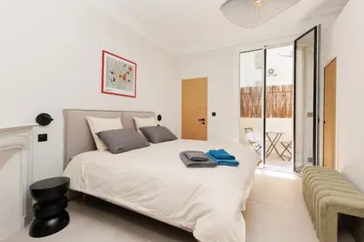 a white bedroom with a large bed and a chair at Sublime appartement Forville Festival in Cannes