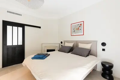 a bedroom with a large white bed with a black door at Sublime appartement Forville Festival in Cannes