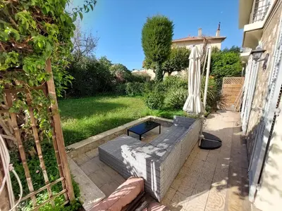 a garden with a bench and an umbrella at Cannes centre avec parking et jardin in Cannes