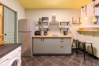 a kitchen with a refrigerator and a counter with chairs at Comfortable apartment in the heart of Suquet in Cannes