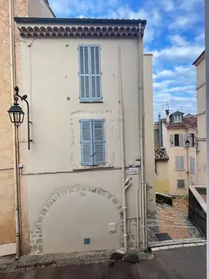 a white building with a blue window and an alley at Comfortable apartment in the heart of Suquet in Cannes