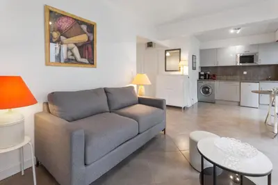 a living room with a couch and a kitchen at Le Vendôme - Hypercentre - AC - Terrace - Palais of Festivals - Croisette in Cannes