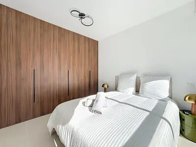 a bedroom with a large bed with a wooden cabinet at 2 pièces vue mer, piscine, à 2 pas des plages in Cannes