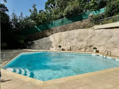 a swimming pool in front of a stone wall at 2 pièces vue mer, piscine, à 2 pas des plages in Cannes