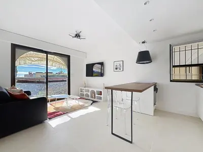 a living room with a table and a couch at 2 pièces vue mer, piscine, à 2 pas des plages in Cannes