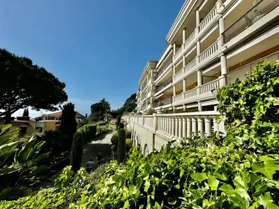 a building with a walkway next to some bushes at 2 pièces vue mer, piscine, à 2 pas des plages in Cannes