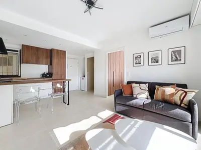 a living room with a couch and a kitchen at 2 pièces vue mer, piscine, à 2 pas des plages in Cannes
