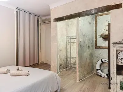 a room with a bed and a clock on a wall at Le Félix - 4 pers 66 m2 - Vieux port - Climatisation in Cannes