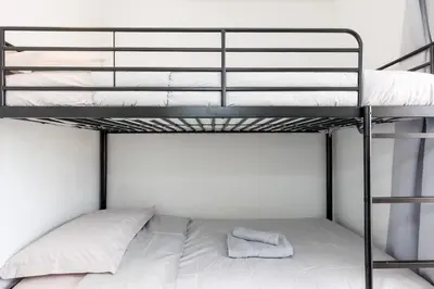 a bunk bed with white sheets and a pillow at Cannes Beach - Vue Mer-Plage-Piscine-Clim-Wifi in Cannes
