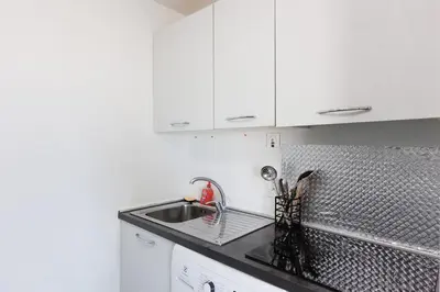 a kitchen with white cabinets and a sink at Cannes Beach - Vue Mer-Plage-Piscine-Clim-Wifi in Cannes