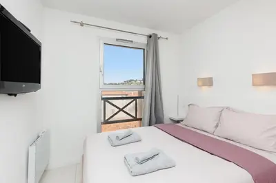a bedroom with a bed and a tv and a window at Cannes Beach - Vue Mer-Plage-Piscine-Clim-Wifi in Cannes