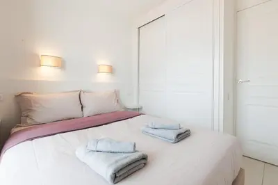 a white bedroom with two towels on a bed at Cannes Beach - Vue Mer-Plage-Piscine-Clim-Wifi in Cannes