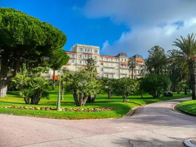 a large building in a park with trees and a road at Appartement Spacieux dans une résidence Haut Standing in Cannes