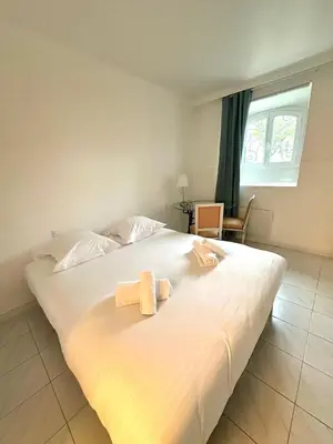 a bedroom with a large white bed with two towels on it at Appartement Spacieux dans une résidence Haut Standing in Cannes