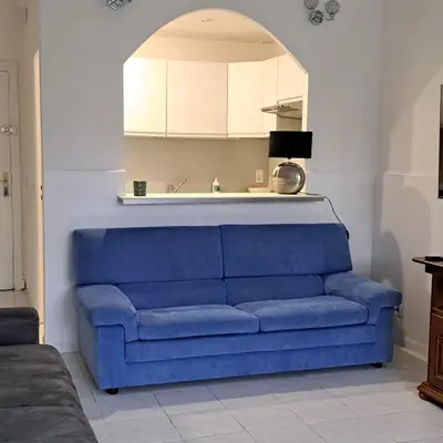 a blue couch in a living room with an arch at Appartement Spacieux dans une résidence Haut Standing in Cannes