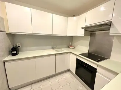 a kitchen with white cabinets and a black dishwasher at Appartement Spacieux dans une résidence Haut Standing in Cannes