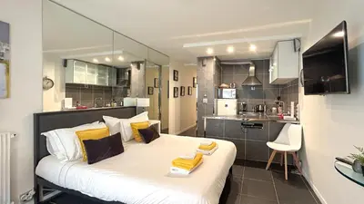 a bedroom with a large white bed with yellow pillows at Studio Victoria 200 m Carlton Hotel & Croisette in Cannes