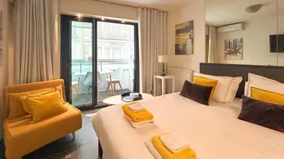 a hotel room with two beds and a chair at Studio Victoria 200 m Carlton Hotel & Croisette in Cannes