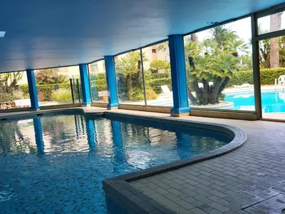 a swimming pool in a building with blue columns at Superbe appartement plage du Midi 2 piscines 325L in Cannes