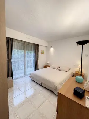 a bedroom with a bed and a large window at Superbe appartement plage du Midi 2 piscines 325L in Cannes