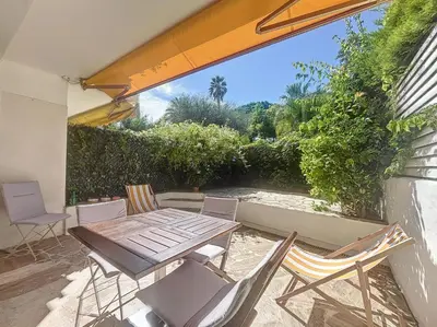 a patio with a wooden table and chairs at A deux pas des plages piscine 346L FRANCHI in Cannes