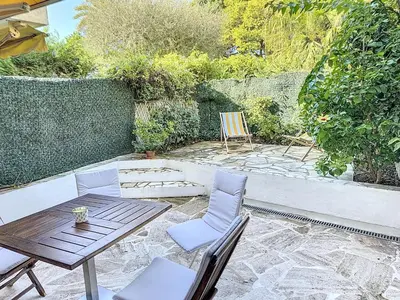 a patio with a wooden table and chairs at A deux pas des plages piscine 346L FRANCHI in Cannes