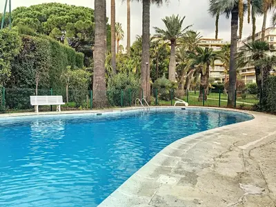 a swimming pool with a bench and palm trees at A deux pas des plages piscine 346L FRANCHI in Cannes