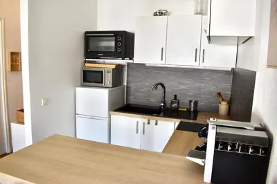 a small kitchen with white cabinets and a microwave at Charming Flat close to palais des festivals in Le Cannet