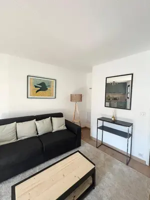 a living room with a black couch and a table at Cosy a 3 min de la plage avec parking privé in Cannes