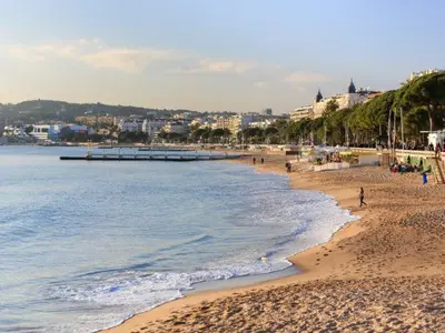 a beach with people walking on the sand and the water at Cosy a 3 min de la plage avec parking privé in Cannes