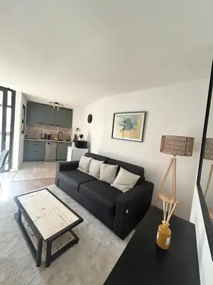 a living room with a black couch and a table at Cosy a 3 min de la plage avec parking privé in Cannes