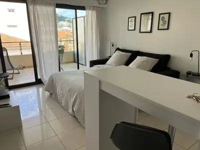 a white bedroom with a bed and a balcony at Studio centre Cannes, piscine, climatisation in Cannes