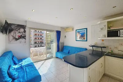 a living room with a blue couch and a kitchen at AHC - Versailles- 2 pièces centre ville in Cannes