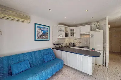 a living room with a blue couch and a kitchen at AHC - Versailles- 2 pièces centre ville in Cannes