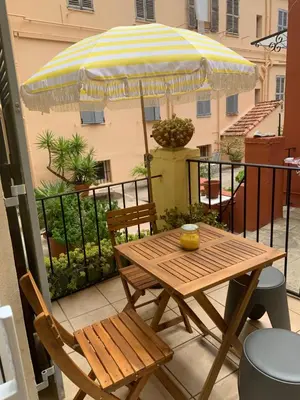 a wooden table and chair with an umbrella on a balcony at Immogroom - Suquet - Vieux Port - Charmant T2 in Cannes